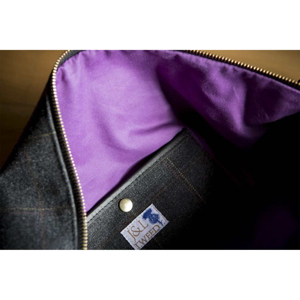 Interior view of coordinating purple lining on the Chambers Weekender Bag in Black Isle tweed with J&L Tweed logo tag